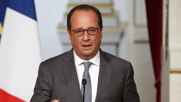 François Hollande spricht vor einer französischen Flagge.
