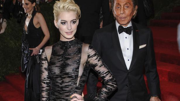 Anne Hathaway und Valentino Garavani auf einem roten Teppich.