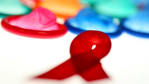 ILLUSTRATION - Eine Aidsschleife und Kondome liegen am Montag (29.11.2010) in Köln auf einem Leuchttisch. Kondome sind der beste Schutz gegen eine HIV-Infektion. Am 1. Dezember ist Weltaidstag. Nach Schätzungen des Aidsprogramms der Vereinten Nationen UNAIDS gibt es weltweit 34 Millionen Infizierte, täglich kommen 7400 dazu. In Deutschland leben rund 70 000 Menschen mit HIV. Die Zahl der Neuinfektionen in der Bundesrepublik lag Ende 2010 bei 3000, etwa 550 Infizierte starben. Foto: Oliver Berg dpa/lnw +++(c) dpa - Bildfunk+++