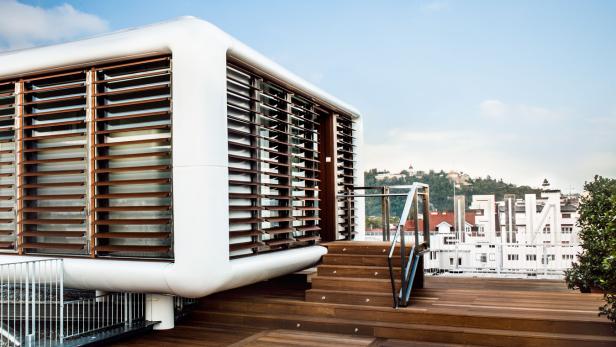 Ein modernes Gebäude mit Holzjalousien auf einer Dachterrasse.