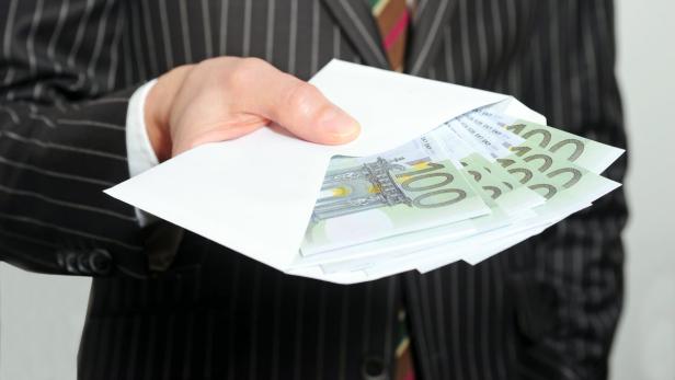 Eine Person im Anzug hält einen Umschlag mit Hundert-Euro-Scheinen.