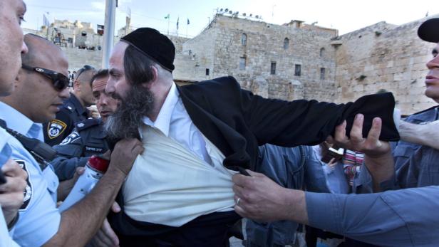 epa03694245 Israeli police scuffle with an ultra-Orthodox Jewish man on the plaza of the Western Wall in Jerusalem, 10 May 2013, as a reform group of Jewish women calling themselves the Women of the Wall held a morning prayer session nearby, complete with prayer shawls, yarmulkes and singing. Huge brawls broke out between ultra-Orthodox Jews, who see the women as a sacrilege to pure Judaism, and the police, who kept the two sides separated. EPA/JIM HOLLANDER