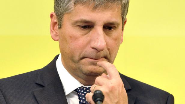 Ein nachdenklicher Mann im Anzug hält einen Finger an die Lippe.