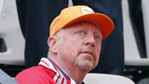 Boris Becker mit orangefarbener Kappe bei einem Tennismatch.