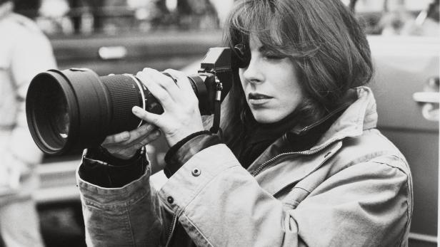 Eine Frau mit einer professionellen Kamera mit Teleobjektiv fotografiert.