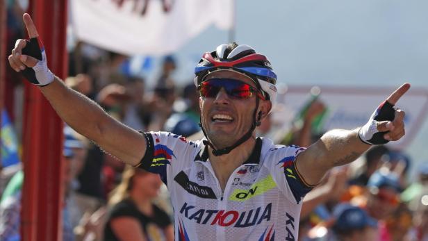 Ein Radrennfahrer jubelt mit erhobenen Armen und Zeigefingern.