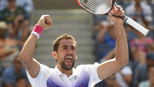 Ein Tennisspieler jubelt mit erhobenen Armen und Tennisschläger.