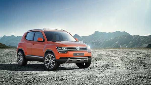 Ein orangefarbener VW Taigun steht vor einer Bergkulisse.