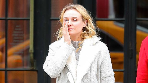 Diane Kruger mit einem grauen Mantel bedeckt ihr Gesicht mit der Hand.