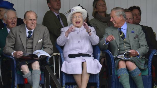 Königin Elisabeth II., Prinz Philip und Prinz Charles lachen zusammen bei einer Veranstaltung.