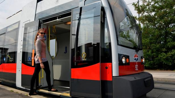 Eine junge Frau steigt in eine moderne Straßenbahn ein.
