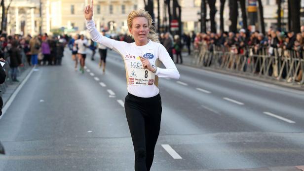 Eine Frau läuft einen Marathon und jubelt mit erhobenem Zeigefinger.
