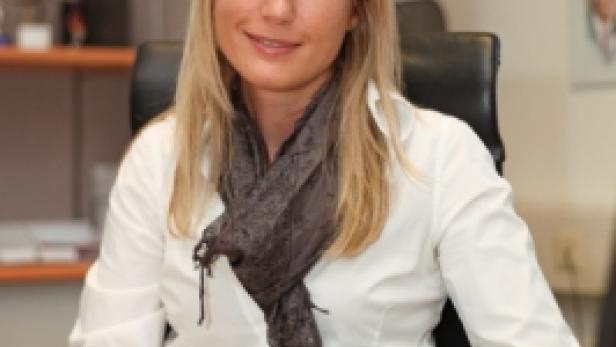 Eine blonde Frau sitzt an einem Schreibtisch in einem Büro.