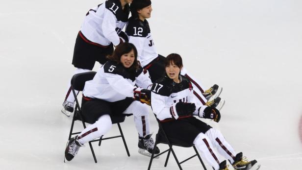 Players of Japan's women's ice hockey team slide o