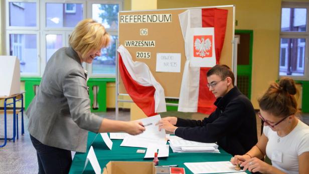 Eine Wahlhelferin nimmt Wahlunterlagen von einem Wähler entgegen.