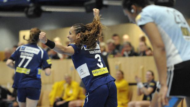 Eine Handballspielerin jubelt mit erhobenen Armen über einen Sieg.