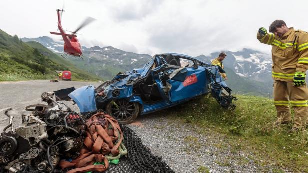Ein schwerer Autounfall in den Bergen, mit Rettungskräften und einem Hubschrauber vor Ort.