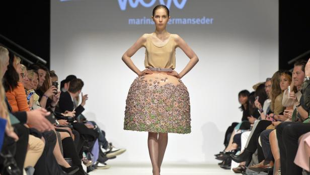 Ein Model präsentiert eine extravagante, blumenbesetzte Rockkreation von Marina Hoermanseder auf dem Laufsteg.