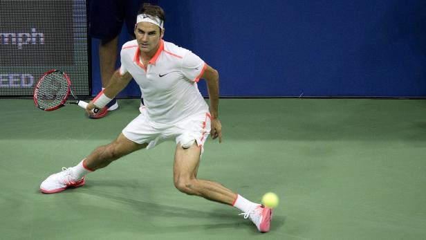 Roger Federer spielt Tennis auf einem grünen Platz.