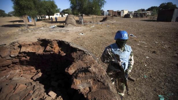 Ein UN-Soldat steht in einem zerstörten Dorf.