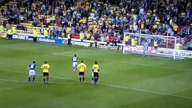 Ein Fußballspieler schießt einen Elfmeter vor einer Zuschauermenge.