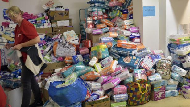Eine Frau packt Windeln in einem Lagerraum voller Windelpackungen.