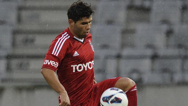 Ein Fußballspieler in roter Spielkleidung jongliert einen Ball.