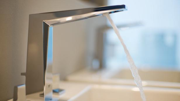 Ein moderner, verchromter Wasserhahn, aus dem Wasser fließt.