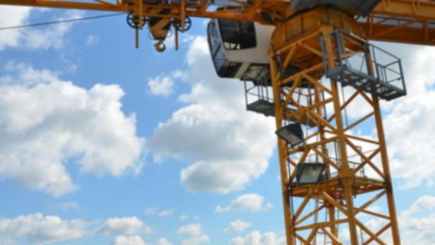 Ein gelber Baukran von Liebherr mit dem Schriftzug „Voitl“ vor blauem Himmel.