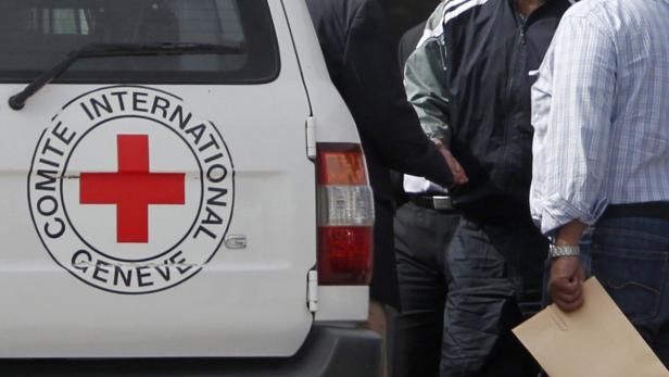 Ein Fahrzeug des Internationalen Komitees vom Roten Kreuz mit Personen im Hintergrund.