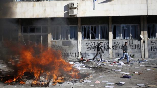 Protesters run near a fire set in front of a gover