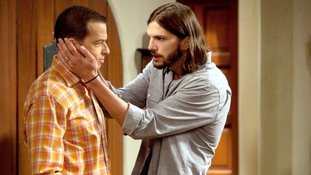 Ashton Kutcher berührt Jon Cryers Gesicht.