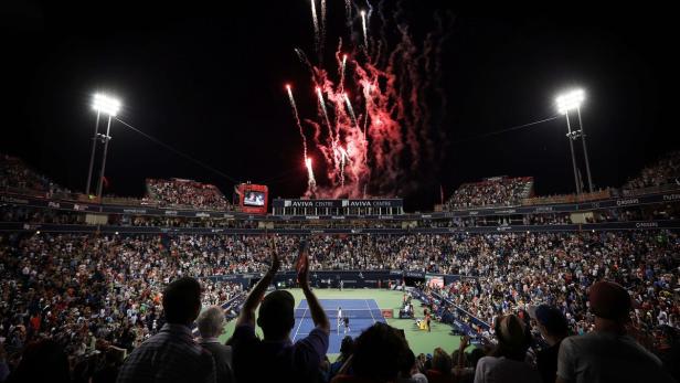 Ein Tennisstadion ist nachts mit Feuerwerk gefüllt.