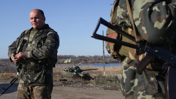 Ukrainische Soldaten stehen vor einem Panzer mit ukrainischer Flagge.