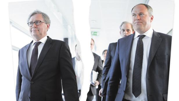 Zwei Männer in Anzügen gehen einen Flur entlang, getrennt durch einen Riss im Bild.