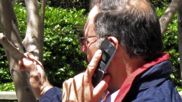 Ein Mann telefoniert im Freien mit einem Klapphandy.