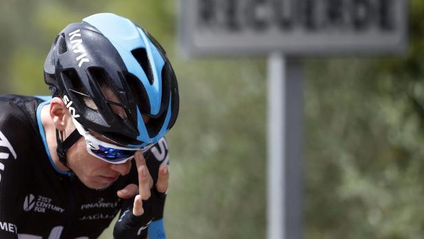 Ein Radfahrer mit blau-schwarzem Helm und Sonnenbrille fährt auf einer Straße.