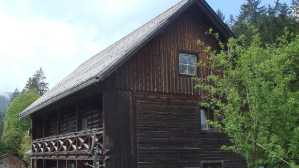 Ein zweistöckiges Holzhaus mit einem Balkon und einem grauen Dach.