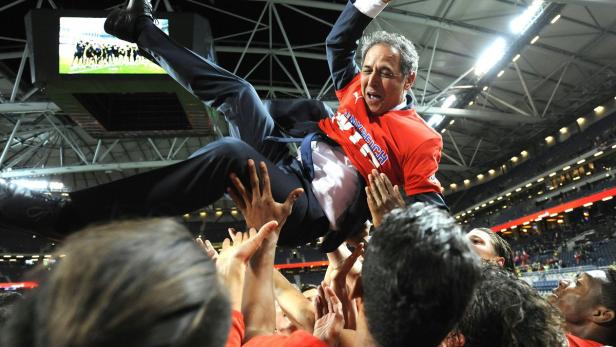 Eine jubelnde Menschenmenge trägt einen Mann in einem roten T-Shirt auf ihren Händen.