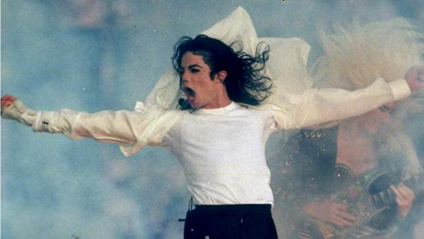 Michael Jackson steht mit ausgestreckten Armen auf der Bühne.