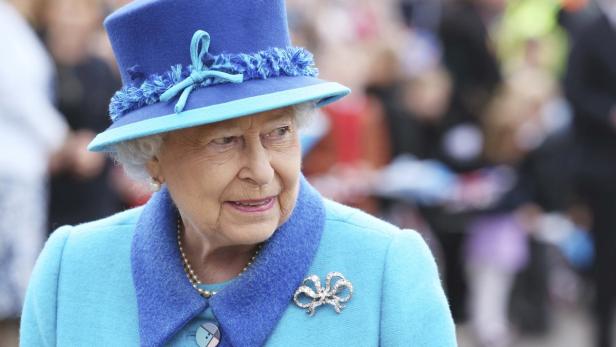 Königin Elisabeth II. trägt einen blauen Hut und ein blaues Kostüm.