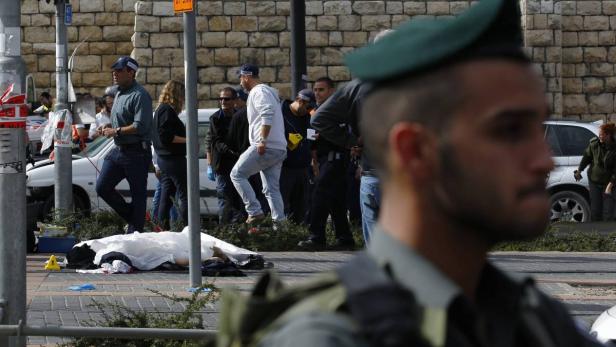 The covered body of a Palestinian motorist lies on