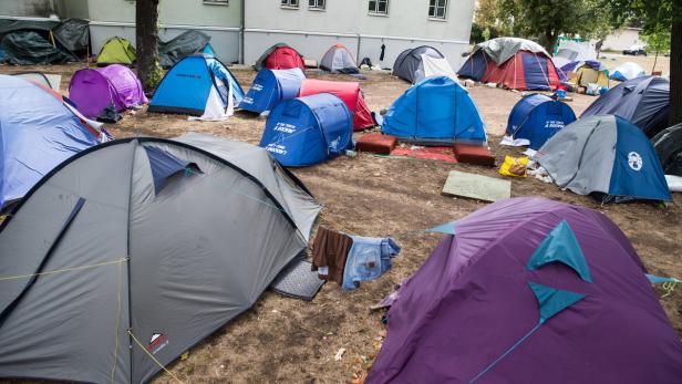 Viele bunte Zelte stehen auf einer Wiese vor einem Gebäude.
