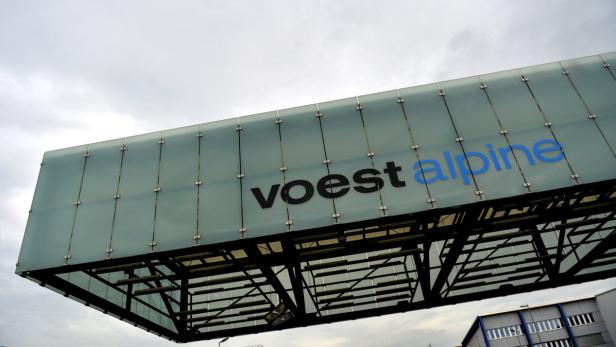 Das Voestalpine-Logo auf einem modernen Gebäude unter einem bewölkten Himmel.