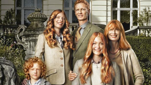 Eine Familie mit roten Haaren posiert vor einem herrschaftlichen Haus.