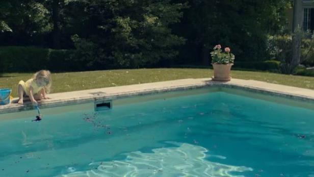 Ein kleines Mädchen spielt am Rand eines Swimmingpools.