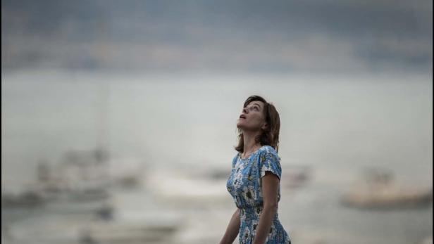 Eine Frau in einem geblümten Kleid blickt zum Himmel.