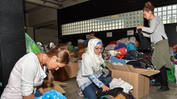 Helfer und Flüchtlinge mit Spenden in der Tabak Fabrik in Linz, in der Flüchtlinge untergebracht werden.