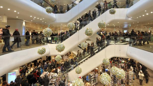 Ein belebtes Einkaufszentrum mit mehreren Rolltreppen und Weihnachtsdekorationen.