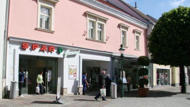 Ein SPAR Gourmet Supermarkt mit Kunden auf einer belebten Straße.